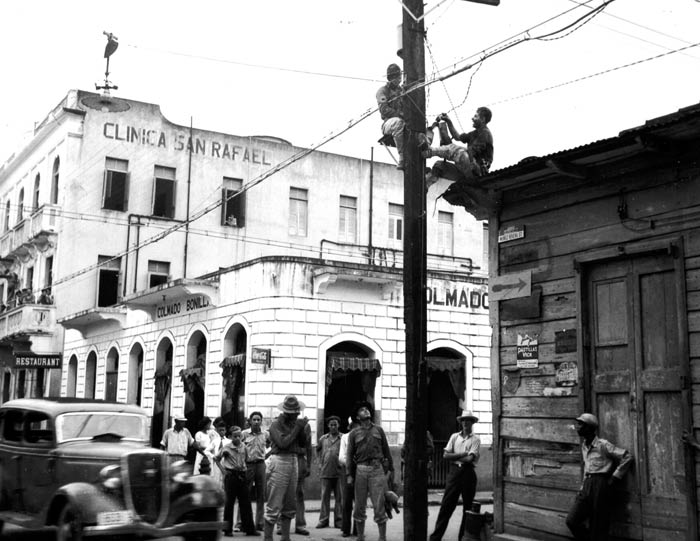 In the town of Caguas, Puerto Rico, 1st Lt. Cipriani, communications officer of the 65th Infantry, accompanied by Sgt. Navares, supervises the work of Tech. Sgt. Santiago and Pvt. Rafael Rivera. November 1941.  SC 126169